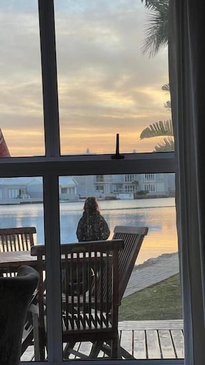 Vista de um quarto com uma janela grande para um corpo de água e edifícios.