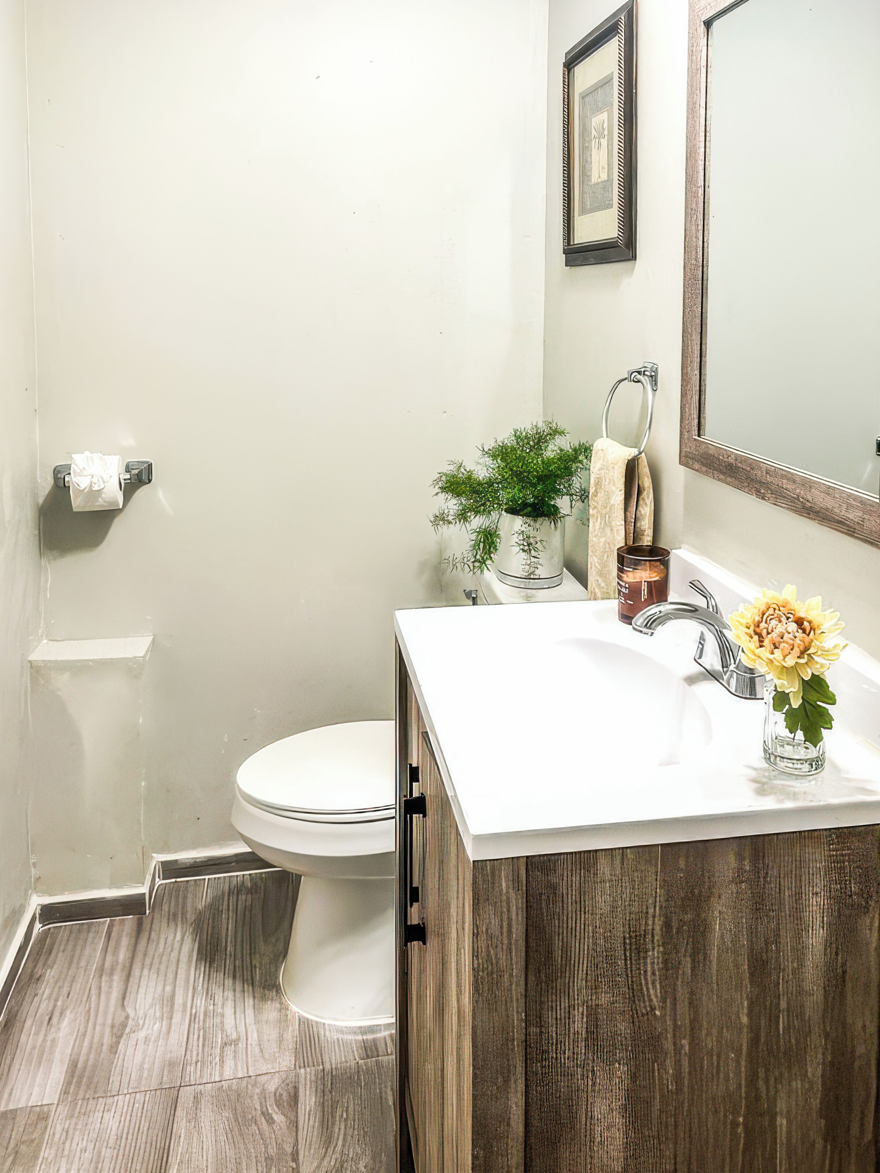 Un baño con inodoro, lavabo, espejo y una planta en maceta.