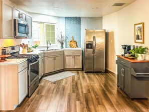 Una cocina moderna con electrodomésticos de acero inoxidable, piso de madera y un revestimiento de ladrillo integrado.