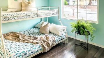 A bunk bed room with a window, a potted plant, and a view of the outside.