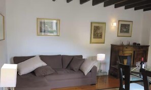 Ein Wohnzimmer mit einer Couch, einem Tisch mit Stühlen und gerahmten Bildern an der Wand.