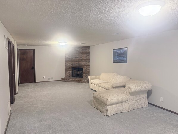 A living room with a fireplace, a sofa, and a carpeted floor.