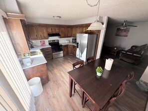 A kitchen with wooden cabinets, a stainless steel refrigerator, a built-in oven, and a dining table with chairs.
