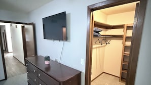 Una habitación con un aparador, un televisor montado en la pared y un armario con una escalera.