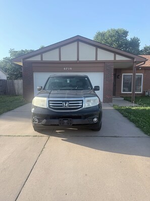 A black Honda SUV parked in front of a garage with the number 8716 on the garage door.