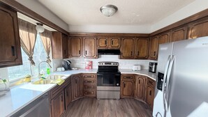 Una cocina con armarios de madera, un refrigerador de acero inoxidable, una estufa y un lavamanos.