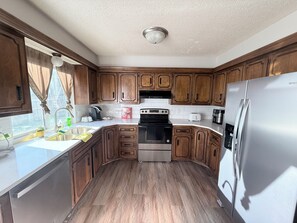 A kitchen with wooden cabinets, a stainless steel refrigerator, a stove, and a sink.