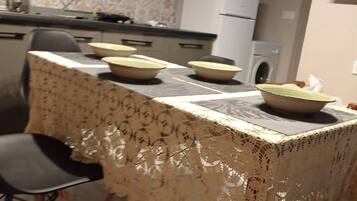 Une table à manger recouverte d’une nappe en dentelle, avec des chaises et des bols disposés dessus.