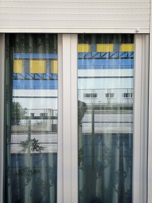 Ein Fenster mit Blick auf ein Mehrgeschosshaus mit Balkon.