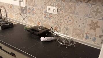 Une cuisine avec des carreaux décoratifs, un plan de travail noir et un four à micro-ondes.