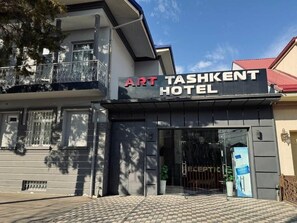 Entrada del Art Tashkent Hotel con un camino de entrada porticado y un cartel.