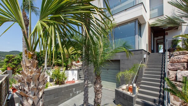 A modern building with a staircase, palm trees, and potted plants. - Villa 'Las Palmeras' for families only with private pool, Wi-Fi and air conditioning (Canet de Mar)