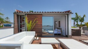 A modern outdoor lounge area with a wooden deck, white sofas, and a glass door leading to a pool area. - Villa 'Las Palmeras' for families only with private pool, Wi-Fi and air conditioning (Canet de Mar)
