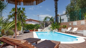 A swimming pool with lounge chairs, a wooden deck, and palm trees. - Villa 'Las Palmeras' for families only with private pool, Wi-Fi and air conditioning (Canet de Mar)