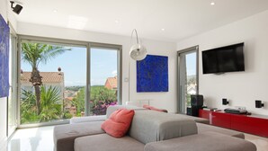 A modern living room with a large sectional sofa, a flat-screen TV, and a view of the outdoors. - Villa 'Las Palmeras' for families only with private pool, Wi-Fi and air conditioning (Canet de Mar)