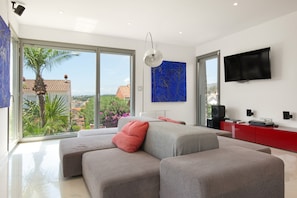 Een moderne woonkamer met een royale hoekbank, een flatscreen televisie en uitzicht op de omgeving.