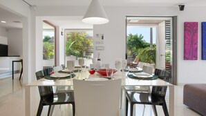 A modern dining area with a white table, black chairs, and a pendant light. - Villa 'Las Palmeras' for families only with private pool, Wi-Fi and air conditioning (Canet de Mar)