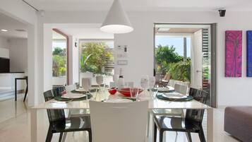 A modern dining area with a white table, black chairs, and a pendant light.