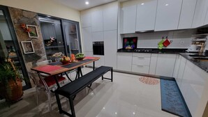 A modern kitchen with white cabinets, a black countertop, and a dining area with a bench and table.