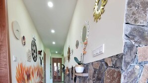 A hallway with a stone accent wall, a decorative mirror, and a wall-mounted clock.