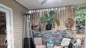 Um pátio com lareira, espaço para sentar, um ventilador e um vaso de planta.