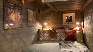 Una habitación acogedora de estilo cabaña de madera, con una cama, almohadas y cuadros en las paredes.