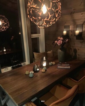 A dining area with a wooden table, candles, and a vase of flowers.