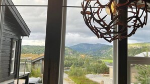 Una habitación con ventanas amplias, una lámpara colgante y vistas a un paisaje montañoso.