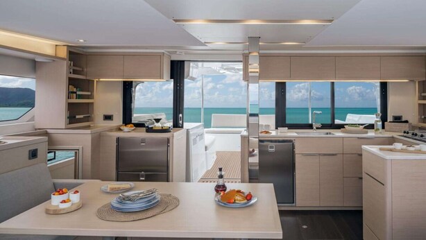 Een moderne keuken met uitzicht op de oceaan, een eethoek met een gedekte tafel voor twee personen, en een bar.