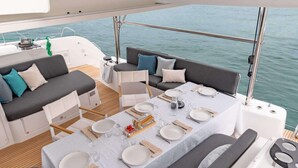 Een eethoek op een boot met een tafel voor vier personen, omringd door comfortabele zitzittingen.