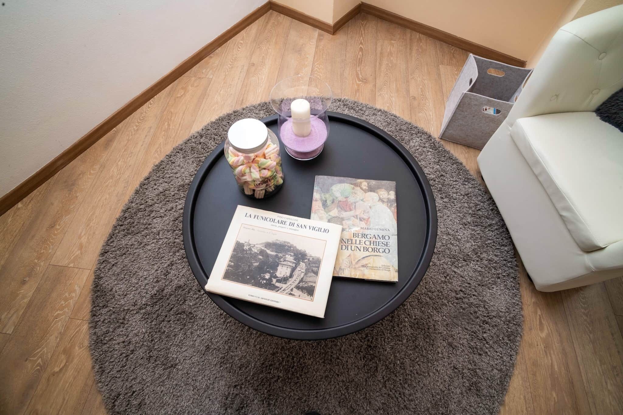 A round black table with a book, a jar of candies, and a candle.