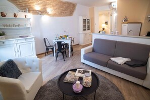 Ein Wohnzimmer mit einer Couch, einem Couchtisch mit einer Kerze und einem Essbereich mit Stühlen und Tisch.