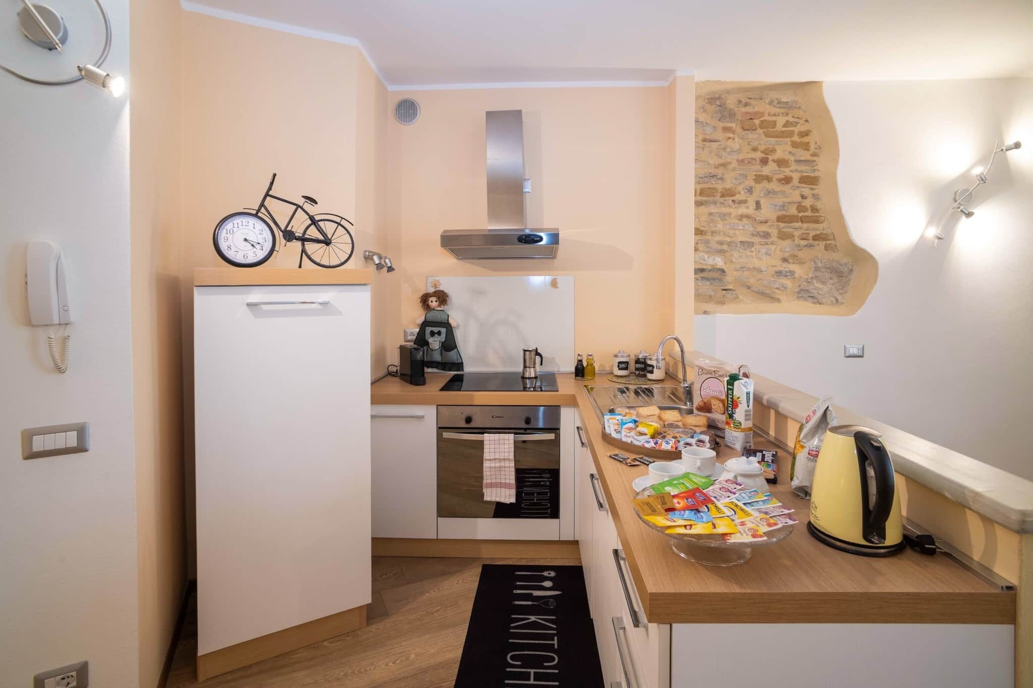 A compact kitchen with a built-in oven, a small refrigerator, and a coffee machine.