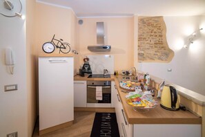 Eine kompakte Küche mit Backofen, kleinem Kühlschrank und einer Kaffeemaschine.