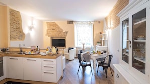 A modern kitchen with a built-in stove, white cabinetry, and a dining area with a table and chairs. - Colleoni 20. Superior Apartment. A stylish apartment for 4 people. Upper Town (Bergamo)