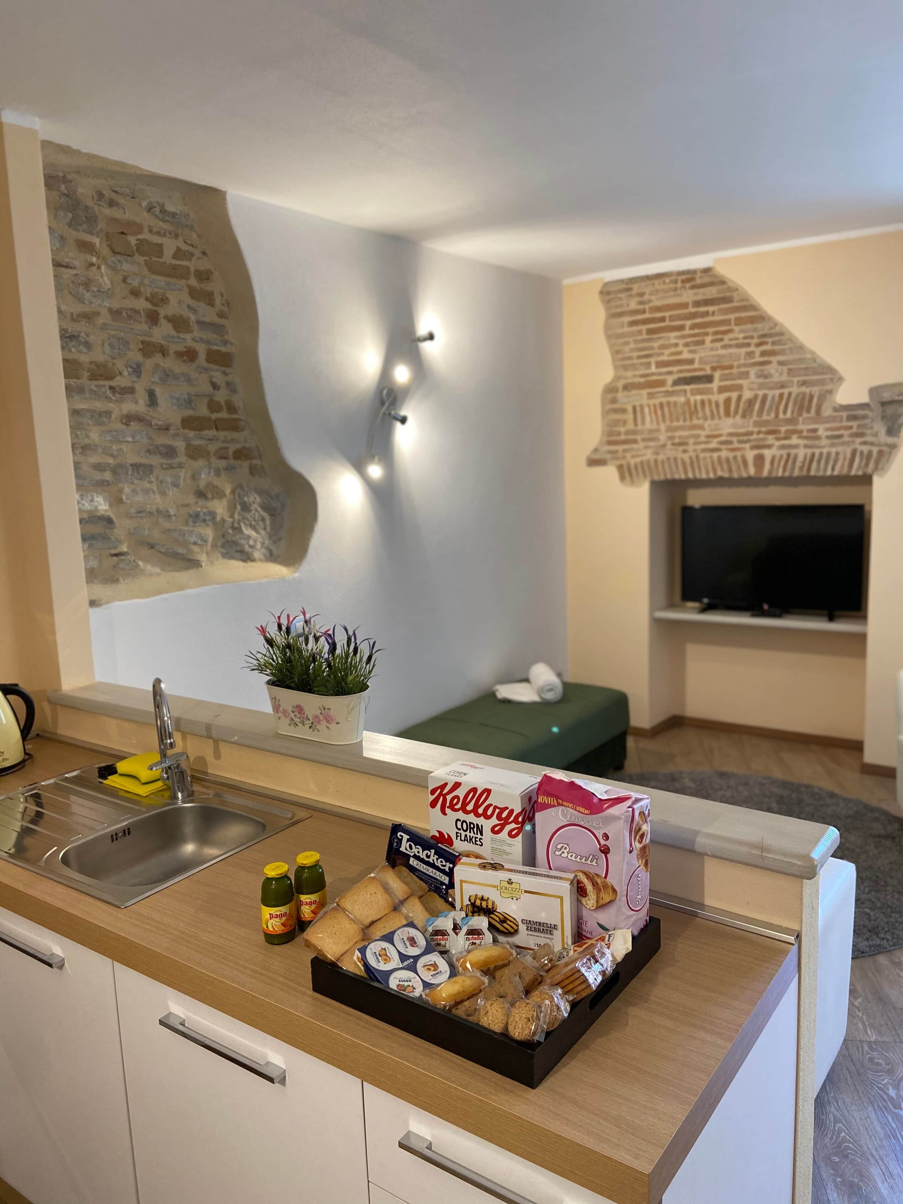 Una cucina moderna con una parete in pietra, un forno integrato e diversi snack e cereali sul bancone.