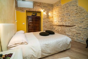 Ein Schlafzimmer mit einem Bett, einer Holzkommode, einer Steinwand und einer Tür.