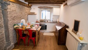 A compact kitchen with a brick wall, wooden ceiling beams, a window, and a white countertop. - The Key to Bergamo.  Il Capitello is a stylish apartment located at 112 Via Pignolo (Bergamo)