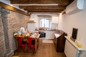 A compact kitchen with a brick wall, wooden ceiling beams, a window, and a white countertop. - The Key to Bergamo.  Il Capitello is a stylish apartment located at 112 Via Pignolo (Bergamo)