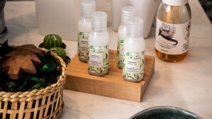 A bathroom with a marble wall, a white soap dispenser, a bamboo diffuser, and a green bowl. - The Key to Bergamo.  Il Capitello is a stylish apartment located at 112 Via Pignolo (Bergamo)