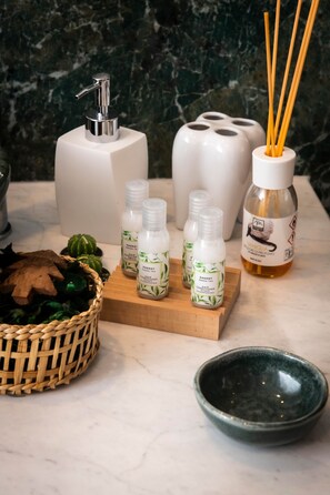 A bathroom with a marble wall, a white soap dispenser, a bamboo diffuser, and a green bowl. - The Key to Bergamo.  Il Capitello is a stylish apartment located at 112 Via Pignolo (Bergamo)