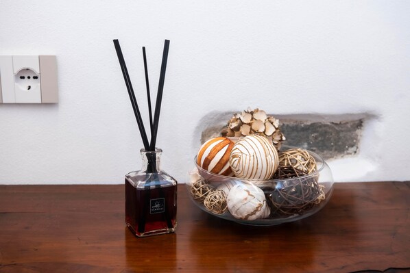 A bottle of perfume, a glass bowl with decorative items, and a power outlet on a wooden surface. - The Key to Bergamo.  Il Capitello is a stylish apartment located at 112 Via Pignolo (Bergamo)
