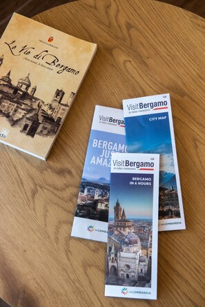 A book titled 'Le Vie di Bergamo' and several pamphlets with city maps and information about Bergamo. - The Key to Bergamo.  Il Capitello is a stylish apartment located at 112 Via Pignolo (Bergamo)