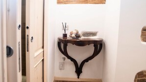 A narrow hallway with wooden flooring, a white door, and a small table with a shelf above it. - The Key to Bergamo.  Il Capitello is a stylish apartment located at 112 Via Pignolo (Bergamo)