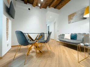 A modern living room with a dining area, a grey sofa, and a TV mounted on the wall. - Lovely Home Bergamo: A stylish, renovated apartment in the heart of Bergamo (Bergamo)