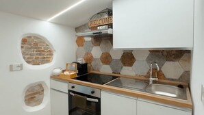 Une cuisine compacte équipée d’un four encastré, d’un évier et d’une pancarte « BIENVENUE » au-dessus de la cuisinière.