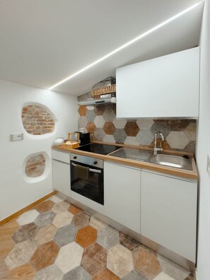 A compact kitchen with a built-in oven, a sink, and a 'WELCOME' sign above the stove. - Lovely Home Bergamo: A stylish, renovated apartment in the heart of Bergamo (Bergamo)