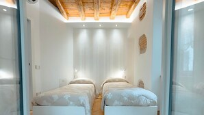 Une chambre avec deux lits, un plafond en bois et une cloison en verre.