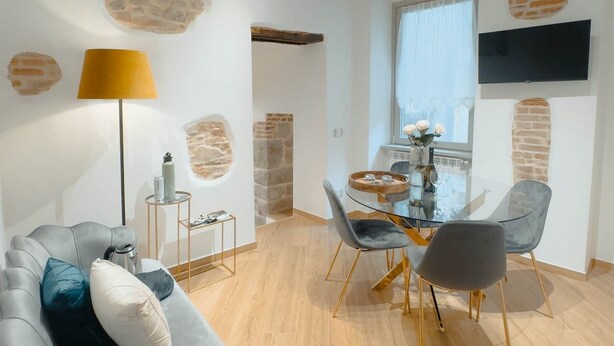 Un salon moderne comprenant un canapé, une table à manger et des chaises, une lampe et un téléviseur fixé au mur.