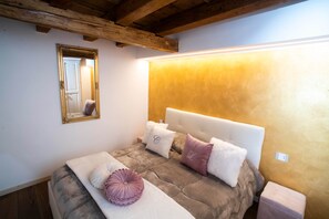 Ein Schlafzimmer mit einem Bett, einem Nachttisch, einem Spiegel und einer Wandleuchte.